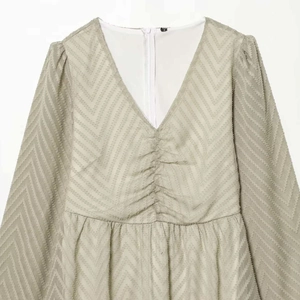Pale apricot pleated long-sleeve dress with a V-neck and delicate wave texture