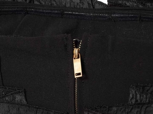 Detail of a high-quality gold metal zipper on a black textured fabric strapless top