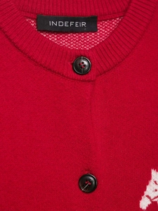Detailed macro view of the red knitted cardigan's crew neck and black buttons
