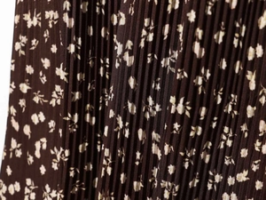 Detailed macro view of dark brown floral pleated fabric texture with white flowers