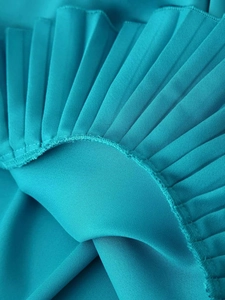 Detail of teal pleated fabric showing high-quality stitching and chiffon texture
