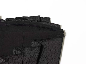 Macro shot of charcoal black textured fabric with ruffled edges and detailed seam work