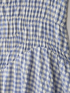 Nahaufnahme von blau-weißem Gingham-Midi-Kleid Stoff mit Smok- und Raffungsdetails