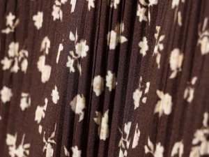 Detail view of brown pleated fabric with white floral print for a V-neck dress