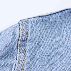 Detail of light blue washed denim dress featuring double yellow contrast stitching and texture