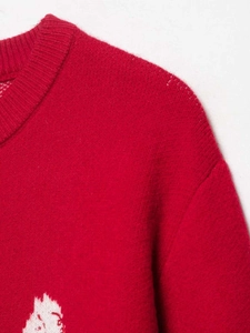 Detail of red knit cardigan with round neck showing soft texture and shoulder seams