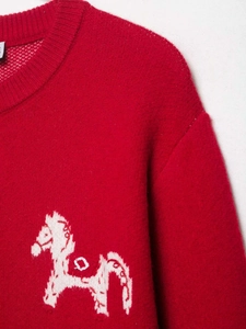 Détail du pull en maille rouge avec un motif jacquard de petit cheval blanc