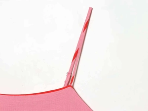 Dettaglio dell'abito a righe rosa con spalline regolabili e fibbie in metallo lucido