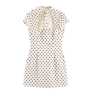 Detail of high neck bow tie and teardrop cutout on cream polka dot mini dress
