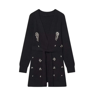 Detail of black knitted cardigan featuring elegant silver rhinestone leaf patterns and waist belt