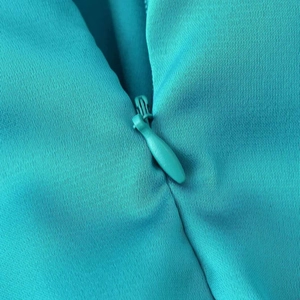 Close-up of invisible turquoise zipper and ruffled texture on an asymmetric summer dress