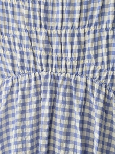 Detail eines blau-weiß karierten Midikleides mit elastischem Smok und Stofftextur