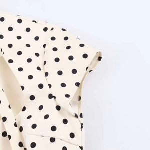 Detailed close-up of cream polka dot fabric stitching and smooth textile texture