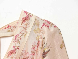 Close-up detail of beige floral dress showing purple blossoms and textured fabric seam