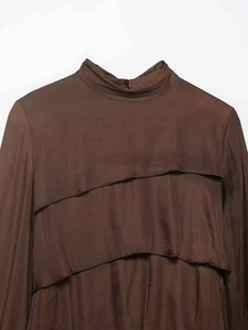 Detail view of brown silk-satin mini dress with high neck and tiered ruffle decorations