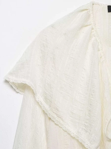 Détail de la dentelle délicate et du tissu à carreaux d'un chemisier blanc chic