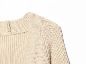 Detailed macro view of beige chunky knit texture and ribbed neckline on cardigan