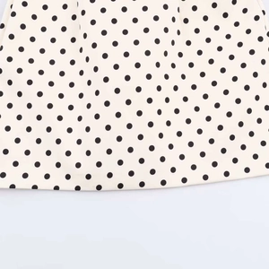Detailed macro shot of vintage polka dot dress fabric with clean hemline stitching