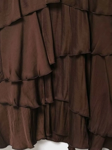 Detail view of smooth coffee satin fabric with layered ruffle and pleated design