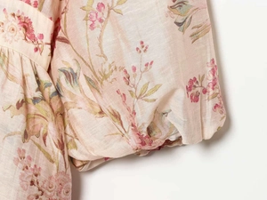 Detailed macro view of retro floral print fabric and elastic smocked puff sleeve cuff