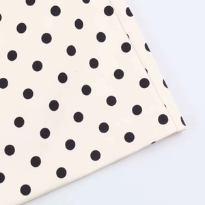 Detailed close-up showing black polka dots on cream textile fabric with neat edge stitching