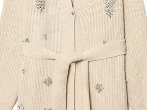 Close-up of beige knit cardigan featuring intricate rhinestone floral beadwork detail