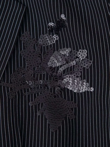 Close-up of sequined floral embroidery on black pinstripe blazer fabric