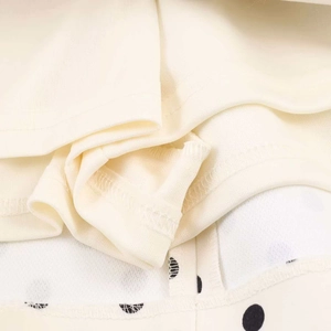 Detail of clean overlock stitching on beige and black polka dot fabric of the dress