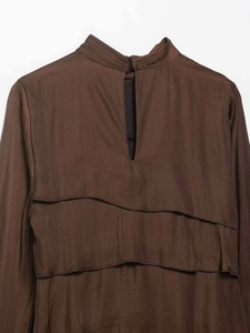 Detail of chocolate brown satin dress with layered ruffles and back cutout with button