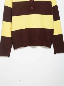 Detail of loose-fit striped knit sweater featuring brown buttons and half-placket collar