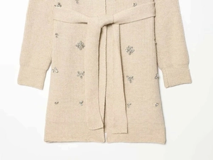 Close-up of beige knit cardigan featuring crystal bead flower embellishments and belt