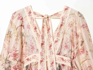Detail of floral printed dress featuring a V-neckline with ties and jacquard texture