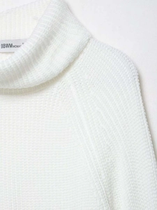 Close-up detail of white high neck knit sweater with textured raglan sleeve and brand neck label