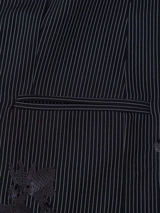 Detail of dark pinstripe fabric with a welt pocket and black floral sequin embroidery