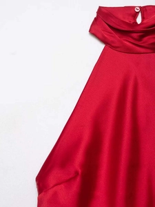 Detailed close-up of a red satin halter neck dress featuring a back button closure