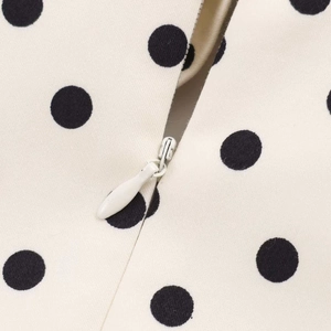 Close-up of invisible zipper detail on white polka dot fabric dress for a seamless finish