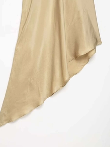 Détail du tissu satiné doré champagne avec un drapé élégant et une couture lisse