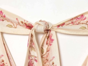 Detail of the waist tie and floral print on a light champagne chiffon dress