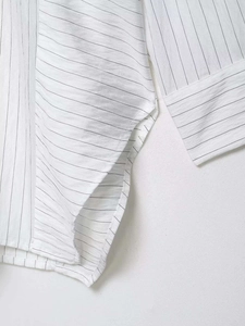 Detailed close-up of fine black pinstripes and neat stitching on a white cotton shirt
