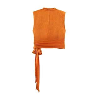 Close-up of orange pleated fabric texture on sleeveless top with waist tie detail