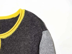 Detail of crew neck knit sweater featuring yellow ribbed collar and color block seams