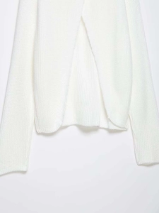 Detail view of the thick knit texture and crossover hem on this white turtleneck sweater