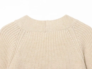 Detail of beige chunky knit cardigan showing raglan sleeves and ribbed neckline