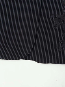 Detailed close-up of black pinstripe fabric with refined sequin floral embroidery