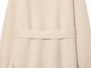 Detail of beige knit cardigan fabric featuring textured weave and matching waist belt