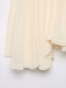 Detail of cream asymmetric hem with frayed edges and layered crepe fabric texture