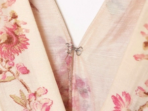 Detailed close-up of V-neckline with metal hook closure on floral print dress