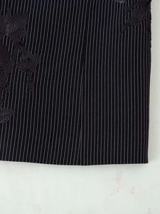 Detail shot of black and white striped blazer featuring shiny black sequin floral embroidery