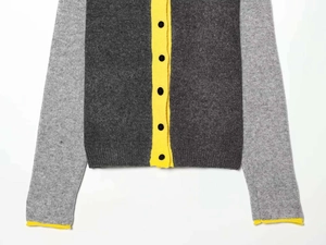 Close-up of the grey knit cardigan showing yellow contrast cuffs and black buttons detail
