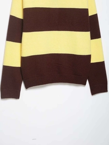 Close-up of the textured knit fabric showing yellow and brown stripes with ribbed cuffs